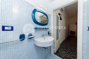 bagno piastrellato blu con lavandino e specchio di La Casina Di Mare a Porto Cesareo
