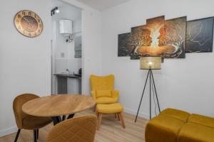 a living room with a table and chairs and a clock at Poznańska 12 by NYX Apart in Skorka