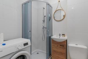 a bathroom with a shower and a washing machine at Poznańska 12 by NYX Apart in Skorka