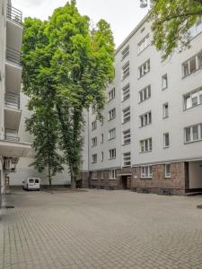 a tree in the middle of a courtyard with two buildings at Poznańska 12 by NYX Apart in Skorka