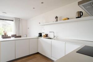 una cucina bianca con mobili bianchi e un lavello di Camiral Golf and Wellness Luxury Villa a Girona