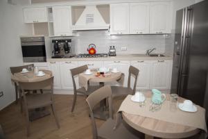 a kitchen with white cabinets and tables and chairs at Villa Caterina Affittacamere in Maratea