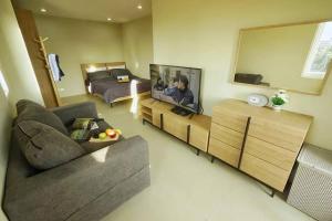 a living room with a couch and a bed and a television at The Two bedrooms Two bathrooms in Phuket Old Town in Phuket
