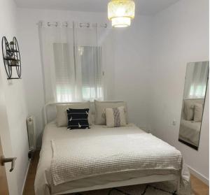 a white bedroom with a bed with pillows on it at Alojamiento espacioso ideal para visitas en grupo in Terrassa
