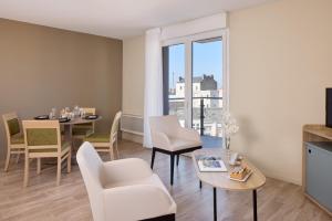a living room with a table and a dining room at Zenitude Hôtel-Résidences Le Havre Les Docks in Le Havre