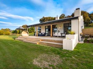 a house with a porch and a lawn at Rhone Hill Polo Club in Plettenberg Bay