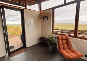 Una habitación vacía con una silla naranja y una ventana. en Valey Luxury - Icelandic Countryside Escape, en Hvammstangi