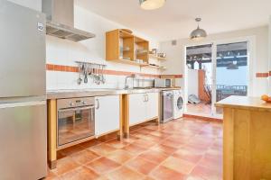 a kitchen with white cabinets and a tile floor at Stunning sea views pool garden in La Herradura