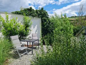 a patio with two chairs and a table in a garden at Ferienwohnung Panoramablick in Bad Mergentheim