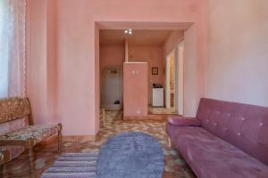 Casa al Castelllo - Traditional home in Parga في بارغا: غرفة معيشة مع أريكة أرجوانية وسجادة