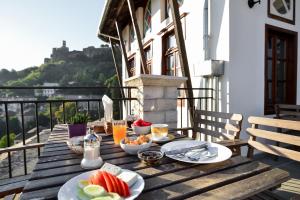 a wooden table with food and drinks on a balcony at Kalemi Twin Boutique Hotel in Gjirokastër