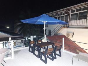 a table and chairs under a blue umbrella on a deck at VBM Carangues in Blue Bay