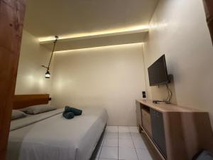 ein kleines Zimmer mit zwei Betten und einem Fernseher in der Unterkunft Buton Backpacker Lodge in Bandung