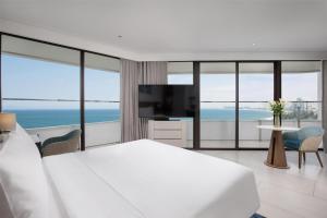 a white bedroom with a large bed and a television at Radisson Hotel Danang in Danang