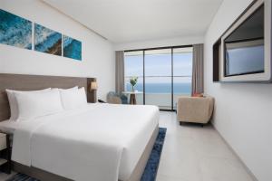 a hotel room with a bed and a view of the ocean at Radisson Hotel Danang in Danang