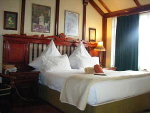 1 dormitorio con 1 cama grande con almohadas blancas en Tudor Lodge Guest House en Johannesburgo