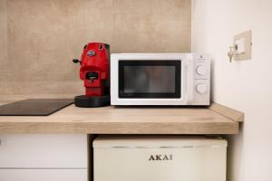 un apparecchio rosso seduto su un bancone accanto a un forno a microonde di Matrice Rooms a Palermo