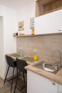 una cucina con lavandino e 2 sedie di Matrice Rooms a Palermo
