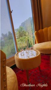 a table with glasses on it in front of a window at Bhurban Nights - Glass Bed Murree Hills View - Lift - 15 Minutes from Murree & Mallroad in Murree