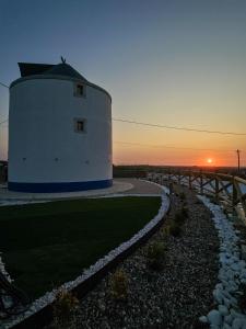 a round building with a sunset in the background at Moinho das Longas in Montelavar +11 photos