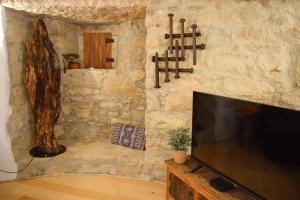 a living room with a tv and a stone wall at Moinho das Longas in Montelavar