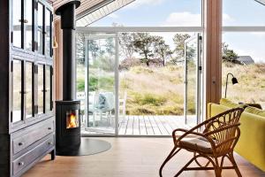 Una sala de estar con chimenea y una silla. en 192-Snedsted-Sarasvej-12, en Snedsted