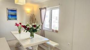 a vase of flowers on a white table in front of a window at Ammos Boutique Rooms-Seafront Stay in Elafonisos in Elafonisos