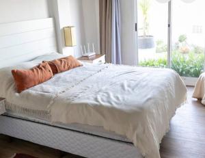 une chambre avec un lit blanc et une fenêtre dans l'établissement Cómoda casa vista espectacular zona Manantiales, à Balneario Buenos Aires