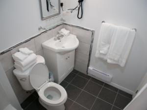 a bathroom with a toilet and a sink and towels at Hotel Le Plaza in La Baie