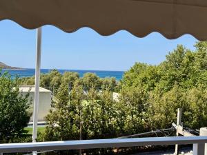 a view of the ocean from a balcony with an umbrella at Diana Seaside Apartment in Anavissos