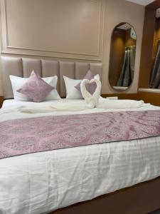 a large bed with purple and white sheets and a mirror at Hotel Shloka in Thane +7 photos