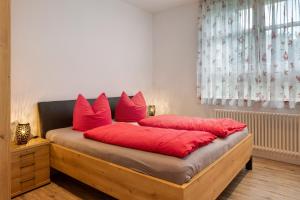 a bed with red pillows on it in a room at Jogis Ferienwohnungen in Freiburg im Breisgau