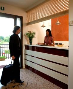 a man and a woman standing at a counter at Albergo Corte di Emma in Arzignano