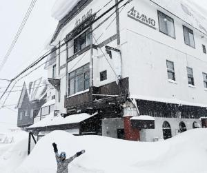 a person standing in the snow in front of a building at Adamo Akakura in Myoko