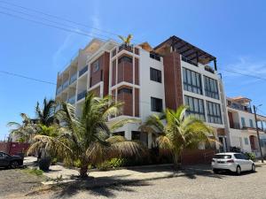 a building with palm trees in front of it at Hotel Por Do Sol in Tarrafal
