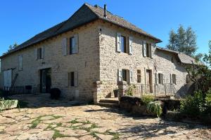 an old stone house with a fence in front of it at Le domaine de verteilhac la grange demile in Banassac