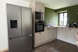 a kitchen with white cabinets and a stainless steel refrigerator at Le domaine de verteilhac la grange demile in Banassac