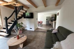 a living room with a green couch and a staircase at Le domaine de verteilhac la grange demile in Banassac