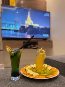 une assiette de fruits et deux boissons sur une table dans l'établissement المها للشقق المخدومة, à Al Thybiyah