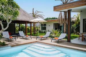 a patio with a pool and chairs and a house at Eko Savannah by MJ Holidays in Tamarin