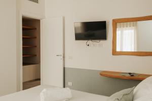 Un dormitorio con una cama y un televisor en la pared. en Bella M'briana, en Polignano a Mare