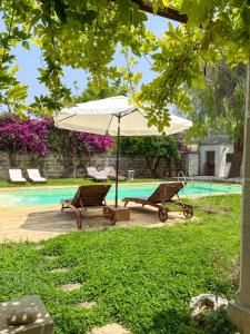 ein weißer Sonnenschirm und zwei Stühle neben einem Pool in der Unterkunft Le Stanze del Monsignore in Novoli + 55 Fotos