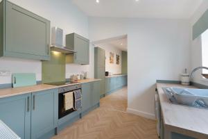 Quarrington HillにあるNew! 4BR in Hill top Houseの青いキャビネットとシンク付きの広いキッチン