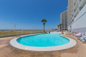 una piscina accanto a una spiaggia con sedie e un edificio di Lighthouse 1004 a Gulf Shores
