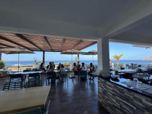people sitting at tables in a restaurant with a view of the ocean at Hotel Por Do Sol in Tarrafal