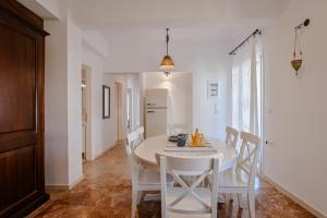 Casa al Castelllo - Traditional home in Parga في بارغا: غرفة طعام بيضاء مع طاولة وكراسي بيضاء