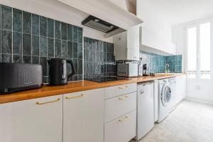 - une cuisine avec des placards blancs et des murs carrelés verts dans l'établissement La Fine Bulle, Appartement de Charme au cœur de Reims, à Reims
