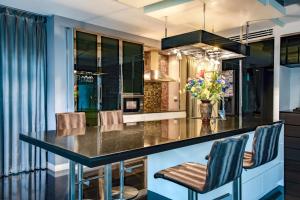 a kitchen with a black counter and chairs at Luxury Pure Modern Pool Villa 5Bed KTV Gym Nr BTS&Central in Bangkok