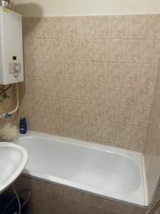 a bathroom with a bath tub and a sink at Kolor House Apartman in Kazincbarcika +11 photos