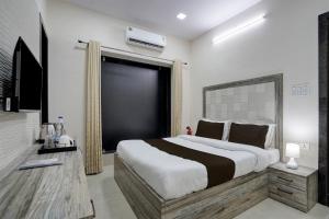 a bedroom with a large bed and a television at HOTEL O AMR GRAND Govindpuri Junction in Kānpur +21 photos